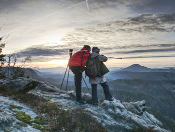 Couple enjoy photographying in wild nature. nature photographers stay on summit rock. listen to muse