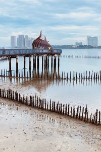 View of wooden posts in sea against sky