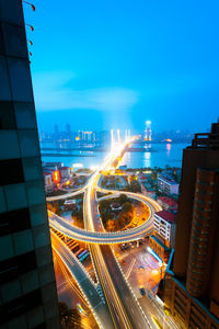 High angle view of light trails on road amidst buildings in city at night