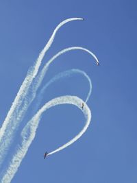 Low angle view of airshow against blue sky