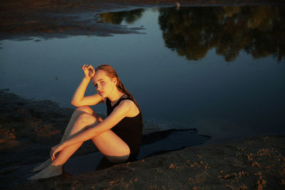 Teenage girl sitting by the lake at beach