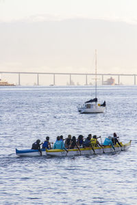 People on boats in sea against sky