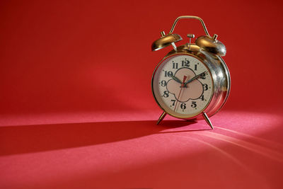 Close-up of clock on table against red background