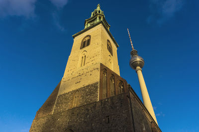 Low angle view of marienkirche by fernsehturm against blue sky