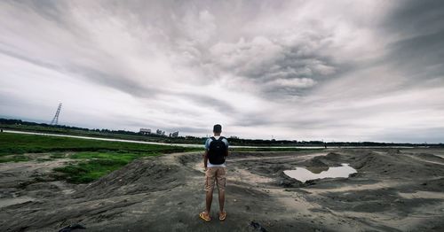 Rear view of man standing on land against sky