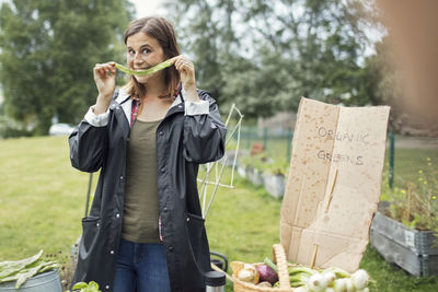 Smiling young woman showing freshly harvested vegetable in urban garden