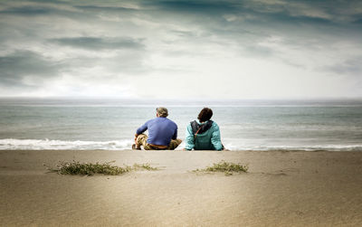 Rear view of men sitting on beach