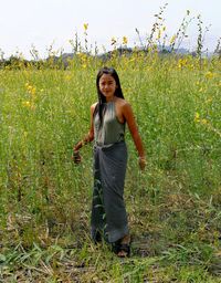 Portrait of smiling young woman standing on field