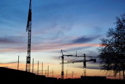 Low angle view of silhouette electricity pylon against sky during sunset