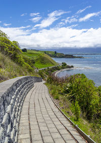 Footpath by sea against sky