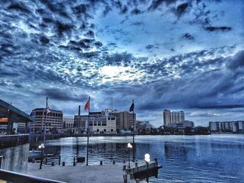 Boats in river against cloudy sky