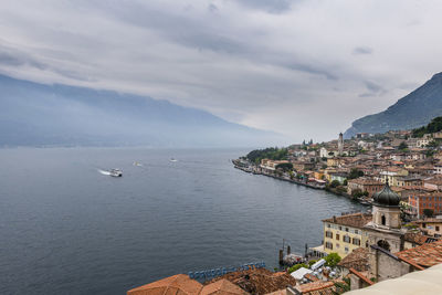 Residential district by lake and mountains against cloudy sky