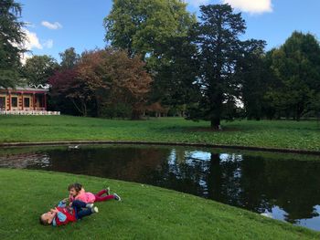 People sitting by lake against trees