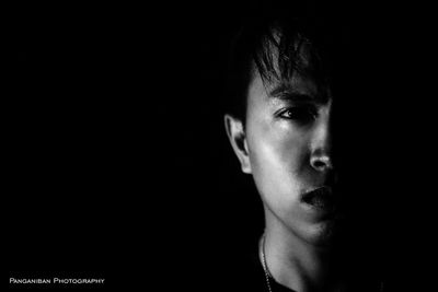 Close-up portrait of young man against black background