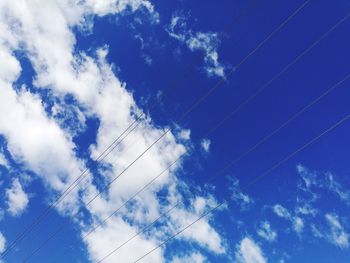 Low angle view of power lines against blue sky