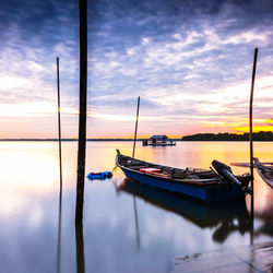 Boat moored on sea against sky during sunset