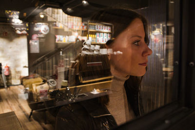 Portrait of woman looking at illuminated restaurant