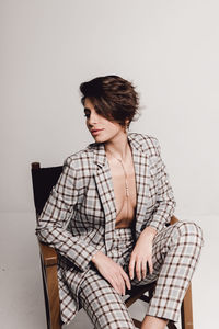 Young woman sitting on chair against white background