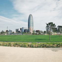 Scenic view of field by buildings against sky