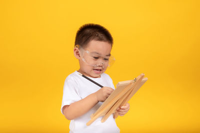 Boy looking away against yellow background