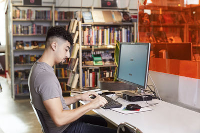 Male student using computer in library
