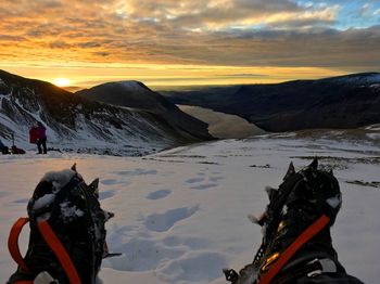 Person in snow covered mountains against sky during sunset