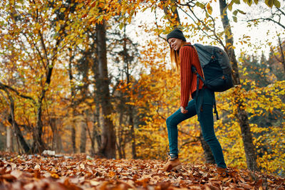 Woman standing by trees in forest during autumn