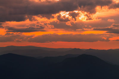 Scenic view of silhouette mountains against orange sky