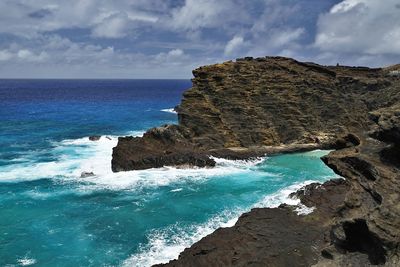 Scenic view of sea by cliff against sky