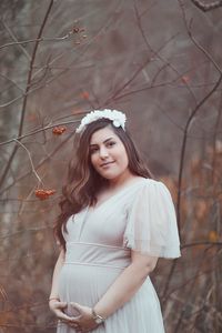 Portrait of young woman standing against tree