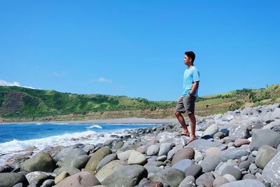 Full length of boy standing on rock at beach