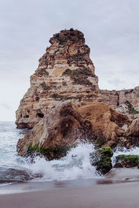 Rock formation on beach against sky