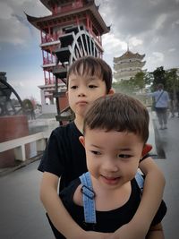 Cute brothers looking away while standing in city