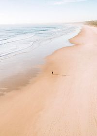 Distant view of person standing at beach against sky
