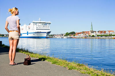 Woman standing in front of city against clear sky