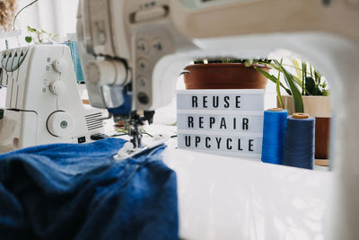 Reuse, repair, upcycle text on light board on sewing machines background. stack of old jeans, denim