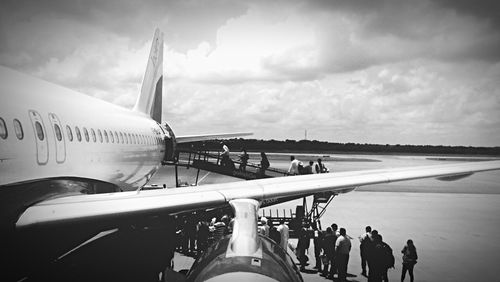People at airport runway against sky