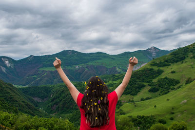 Rear view of woman standing on mountain against sky