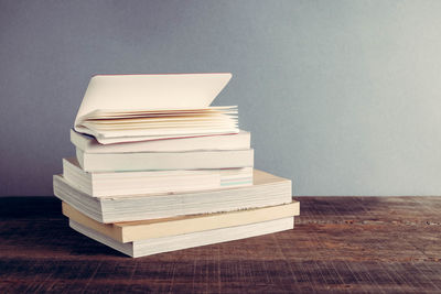 Stacked books on table against gray wall