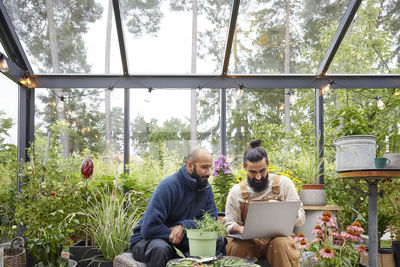 Men using laptop in greenhouse