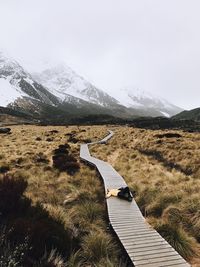 High angle view of man lying on boardwalk against snowcapped mountains