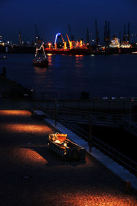 Illuminated harbor by sea against sky at night