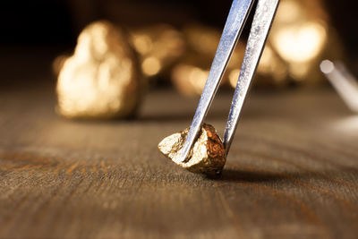 Close-up of gold being held in tweezers on table