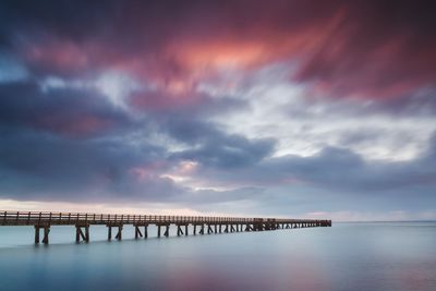 Pier over sea against sky during sunset