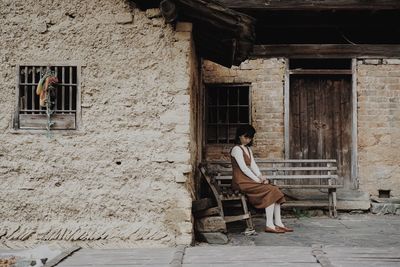 Side view of woman sitting on old building