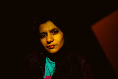 Close-up portrait of young woman against black background