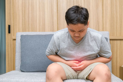 Midsection of teenage girl sitting at home