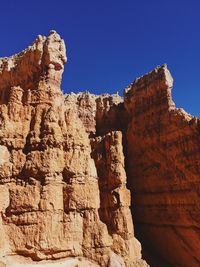 Low angle view of rocky mountain against blue sky