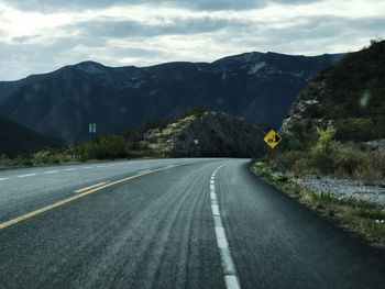 Road leading towards mountains against sky