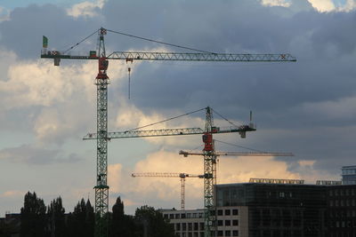 Low angle view of crane in city against sky